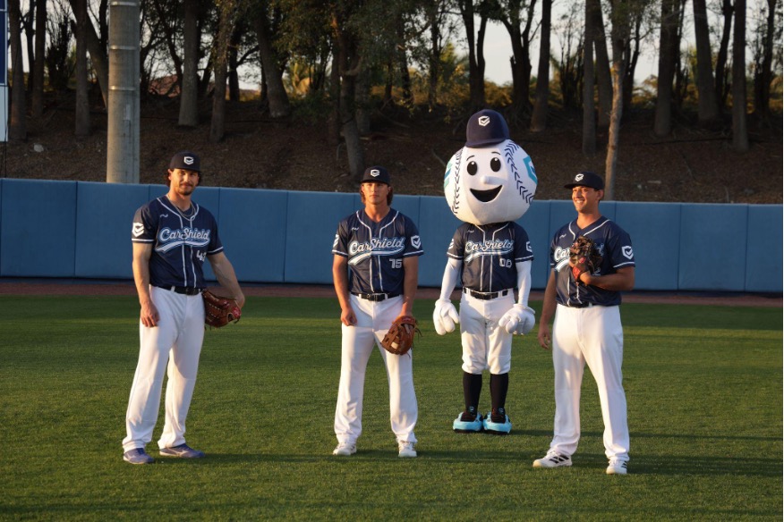 CarShield baseball players and mascot standing in the outfield
