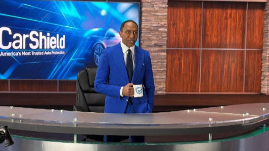 Stephen A Smith behind Carshield desk with a Carshield background